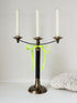 Vintage three arm candelabra in brass and ebonised metal with ivory taper candles styled on a white surface