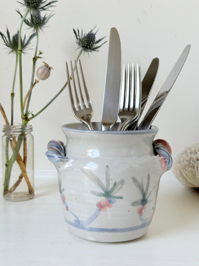 Vintage studio pottery utensil pot with hand painted floral decoration and applied handle detail, photographed on a white surface
