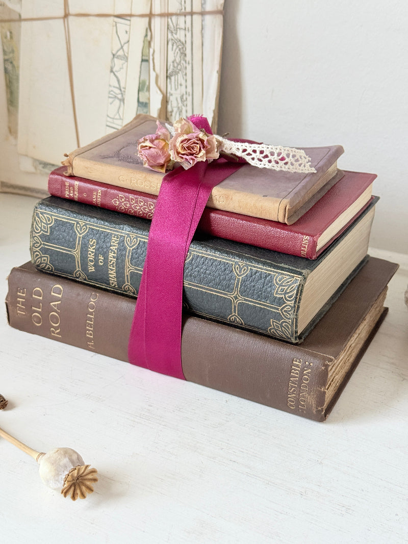 Vintage decorative book bundle with pink ribbon, dried flower detail and aged hardback covers for shelf and table styling