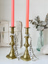Pair of antique brass candlesticks with turned baluster stems and stepped bases holding coral tapers