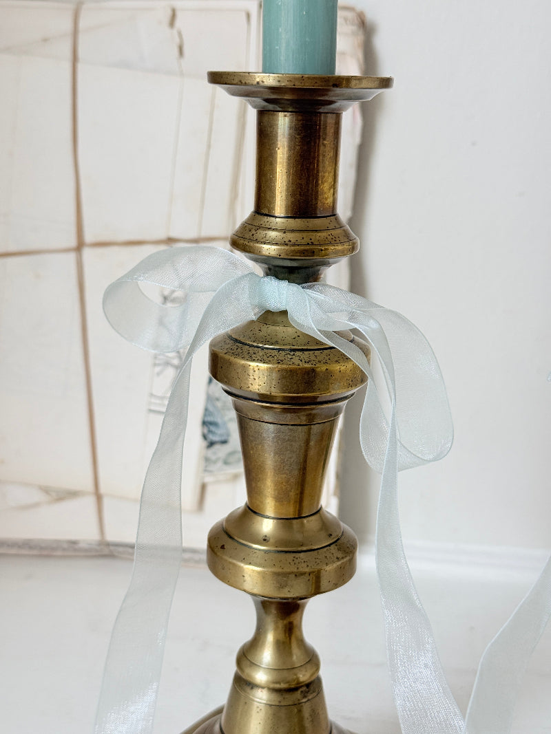 Pair of tall antique brass candlesticks with knopped columns and octagonal stepped bases holding blue and green tapers