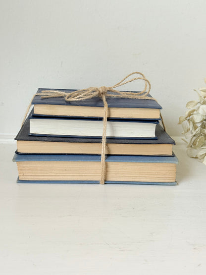Vintage decorative book bundle in navy, grey, and cream tied with twine, photographed on a white surface