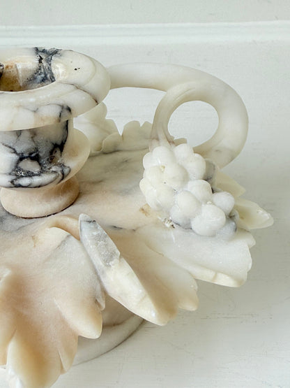 Antique alabaster marble floral candleholder with carved leaves and flowers, photographed on a white surface.