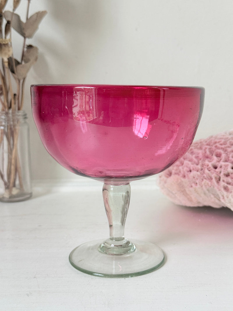 Vintage cranberry glass bonbon dish with clear stem and foot, photographed on a white surface