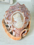 Hand carved cameo helmet shell with a classical female profile in pale relief on pink and brown