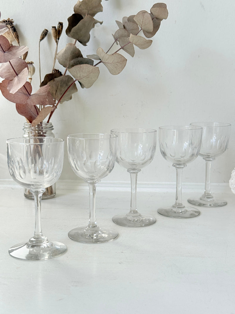 Set of 5 vintage clear glass liqueur glasses with small stems photographed on a white surface