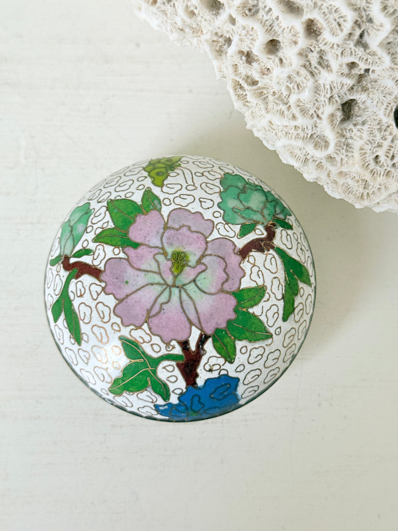 Vintage brass and enamel cloisonne trinket box with floral lid and turquoise interior photographed on a white surface