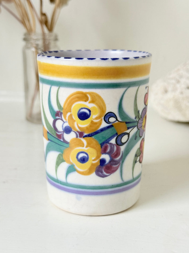 Vintage Poole Pottery pen pot with colourful floral design photographed on a white surface