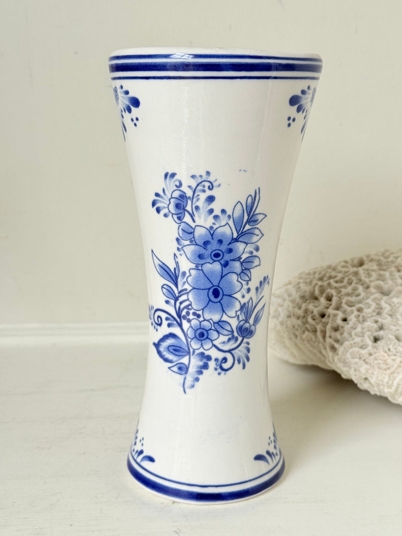 Blue and white Delft hand painted ceramic vase with windmill and floral decoration, photographed on white surface.