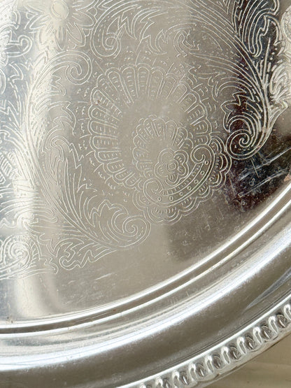 Vintage silver tone round tray with beaded edge, engraved surface detail and reflective finish for drinks or vanity styling