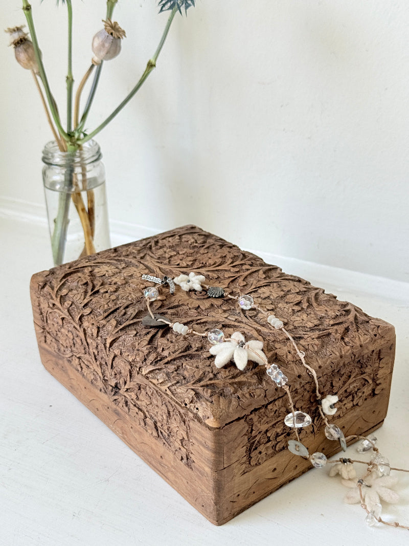 Vintage hand carved wooden jewellery box with floral detail and red fabric lining, photographed on a white surface