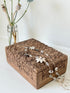 Vintage hand carved wooden jewellery box with floral detail and red fabric lining, photographed on a white surface