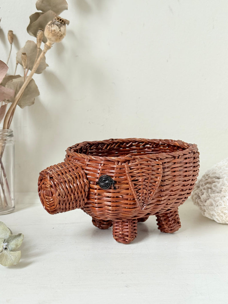 Vintage wicker pig basket planter in warm brown, photographed on a white surface