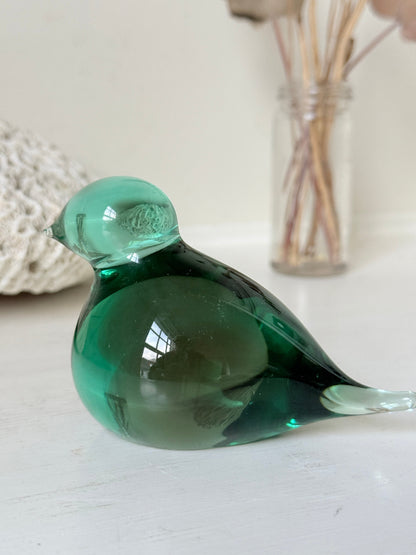 Vintage green glass bird paperweight photographed on a white surface