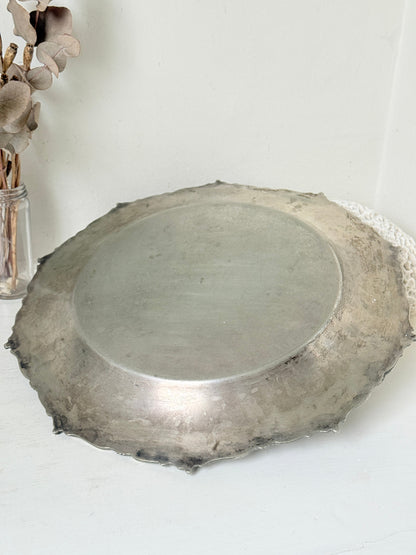 Vintage silvertone metal tray with ornate border, photographed on a white surface