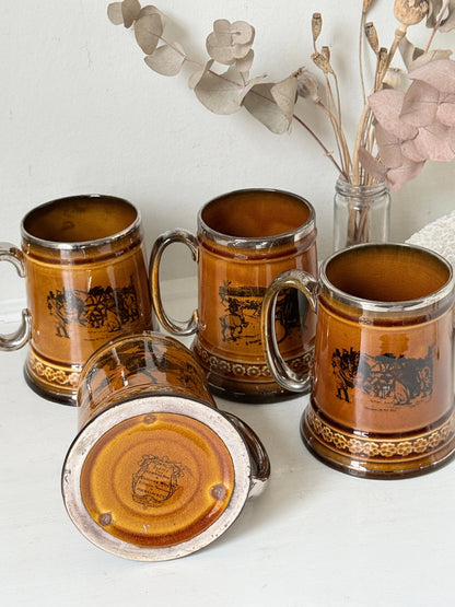 Set of 4 antique Ridgway stoneware beer tankards photographed on a white surface in amber treacle glaze with black Coaching Days and Coaching Ways scenes