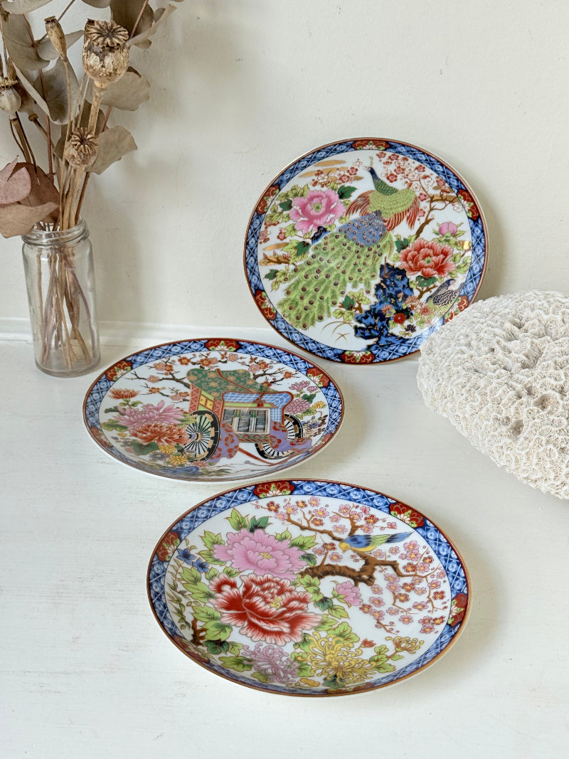 Set of 3 vintage East Asian style decorative hanging plates with peacock and floral design photographed on a white surface
