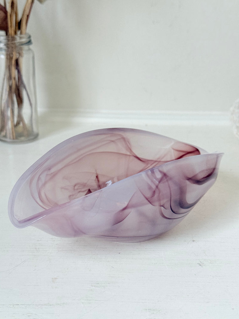 Vintage clam shaped Sowerby glass bowl in lilac purple swirl photographed on a white surface