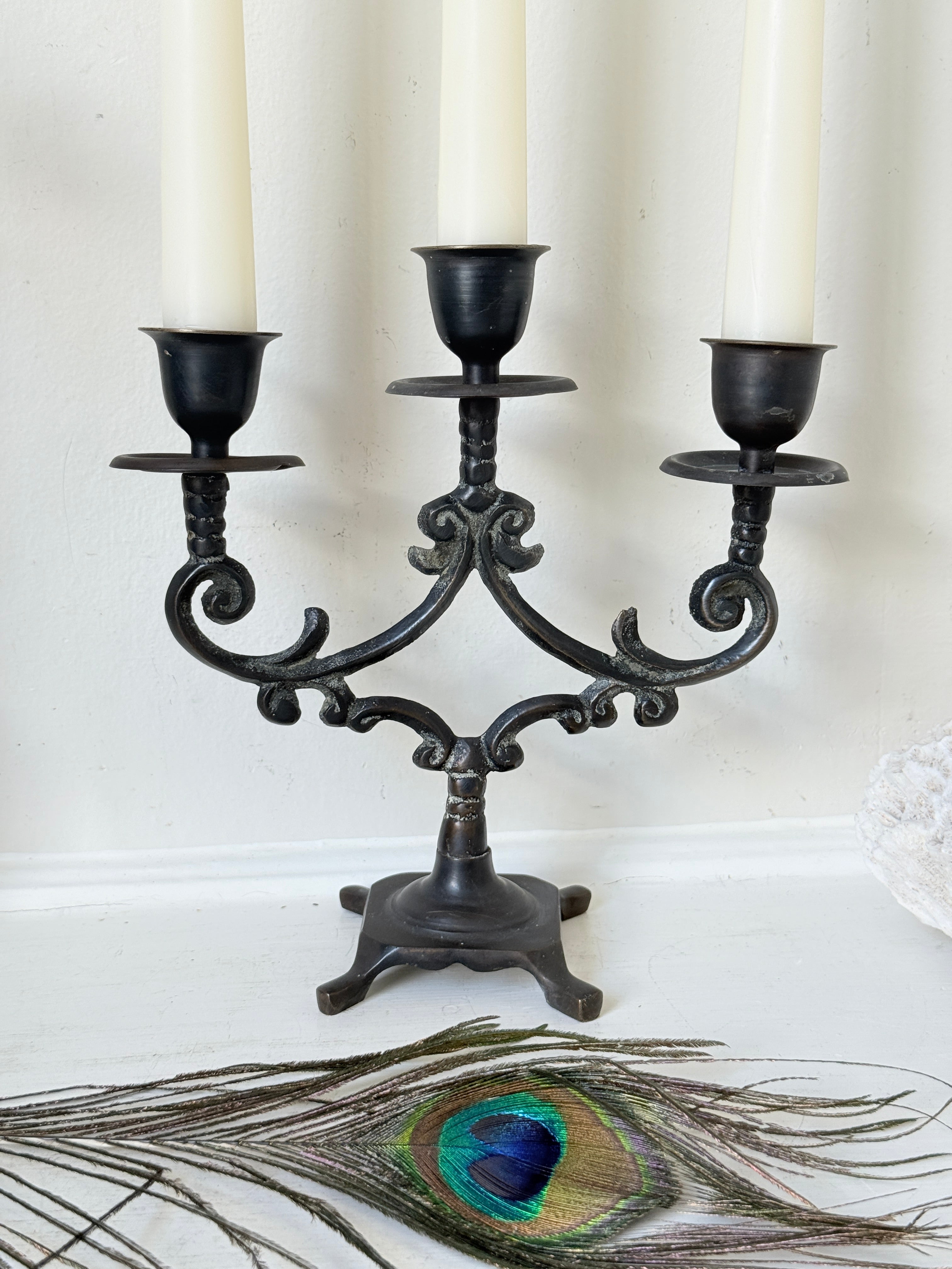 Pair of vintage brass three arm candelabra with scrolling arms and aged patina, photographed on a white surface