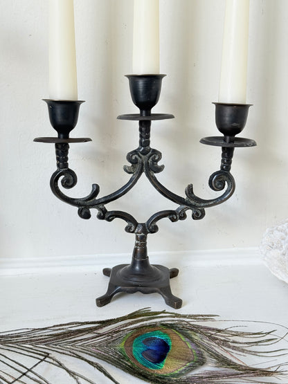 Pair of vintage brass three arm candelabra with scrolling arms and aged patina, photographed on a white surface