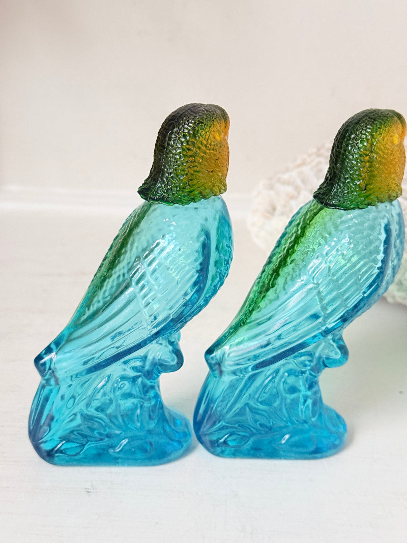Pair of vintage Avon turquoise glass parrot bottles with green amber stoppers photographed on a white surface