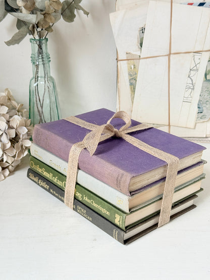 Bundle of vintage books with a heather purple cloth cover over green and cream spines tied with natural twine