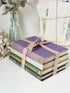Bundle of vintage books with a heather purple cloth cover over green and cream spines tied with natural twine