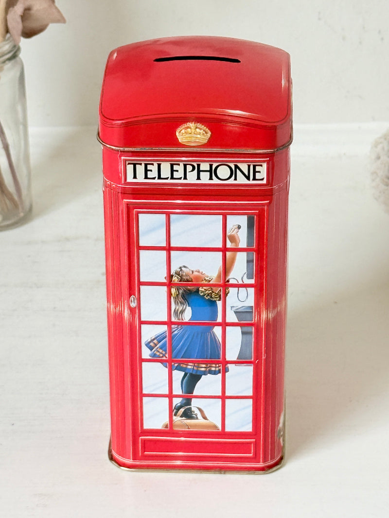 Vintage red telephone box tin money box on a white surface