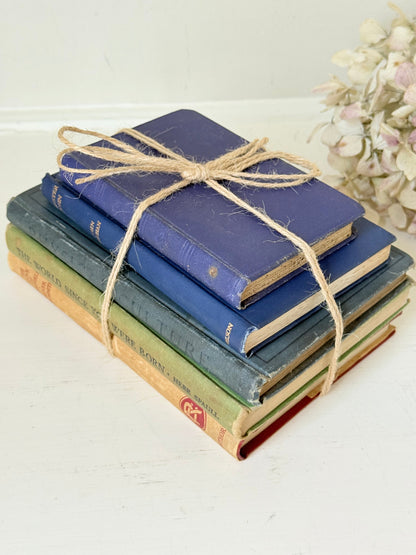 Vintage decorative book bundle in blue and green tied with twine, photographed on a white surface