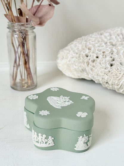 Vintage Wedgwood Jasperware sage green lidded trinket box in a quatrefoil shape, decorated with white neoclassical cherubs and florets, styled with dried stems.