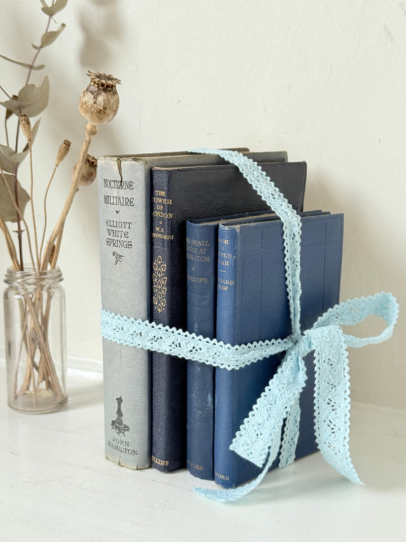 Vintage navy decorative book bundle tied with pale blue lace ribbon, photographed on a white surface