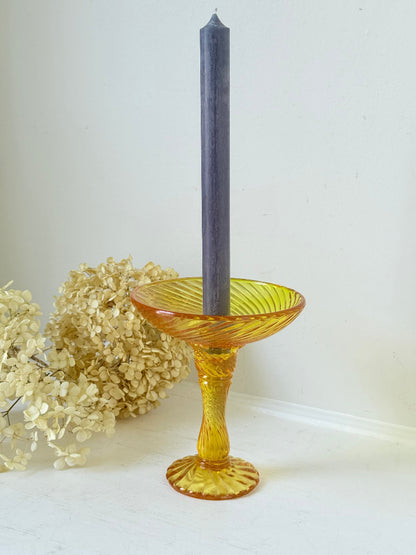 Amber pressed glass candle holder or compote with swirl design and pedestal base, photographed on a white background