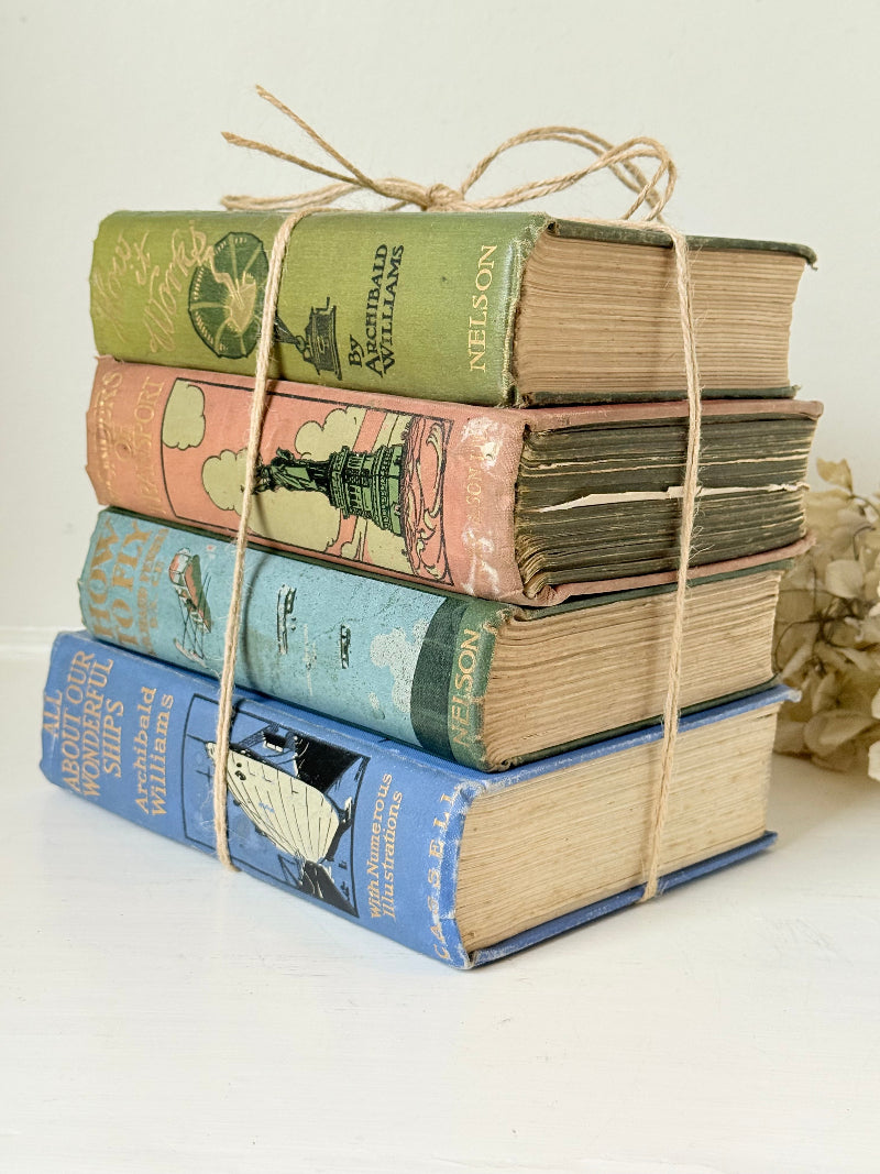Vintage decorative book bundle in green, blue, and coral with printed lettering, tied with twine, photographed on a white surface