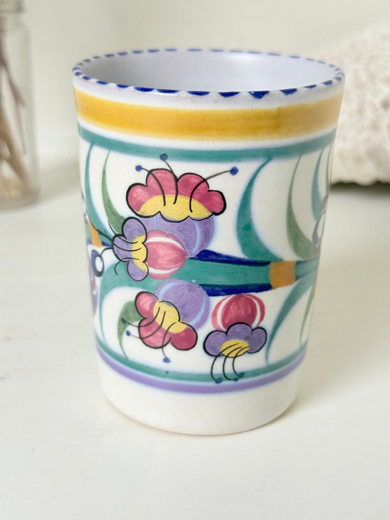 Vintage Poole Pottery pen pot with colourful floral design photographed on a white surface