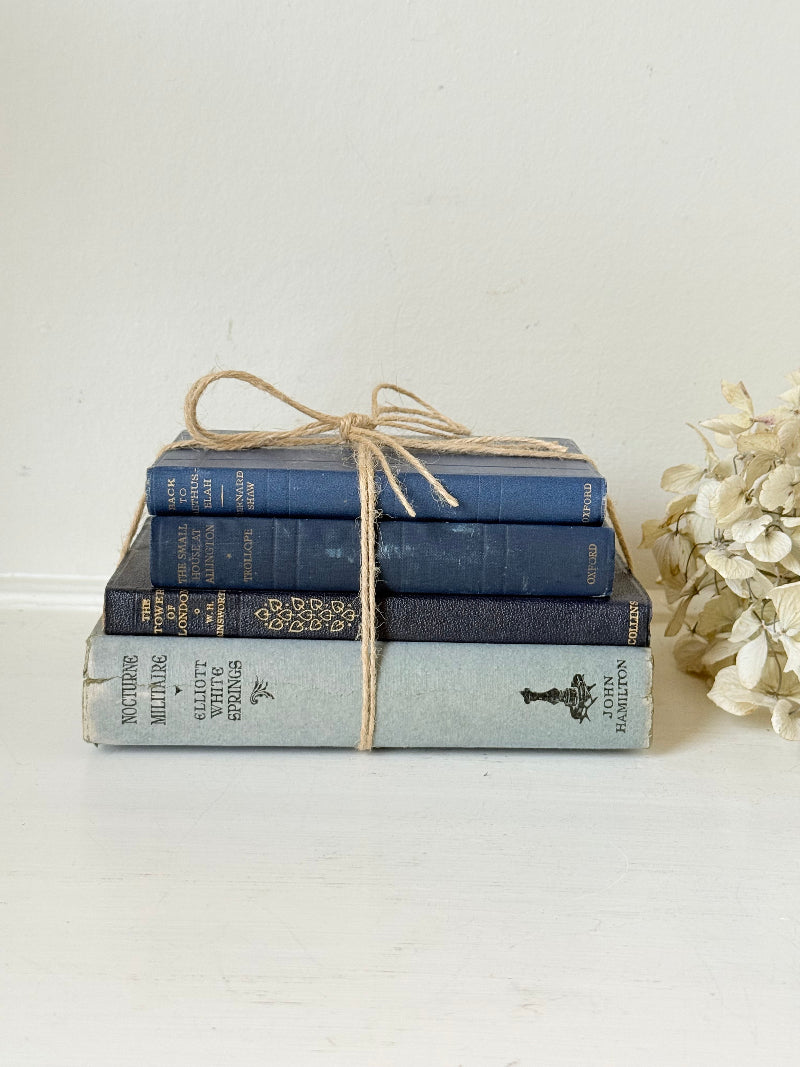 Vintage decorative book bundle in navy, grey, and cream tied with twine, photographed on a white surface