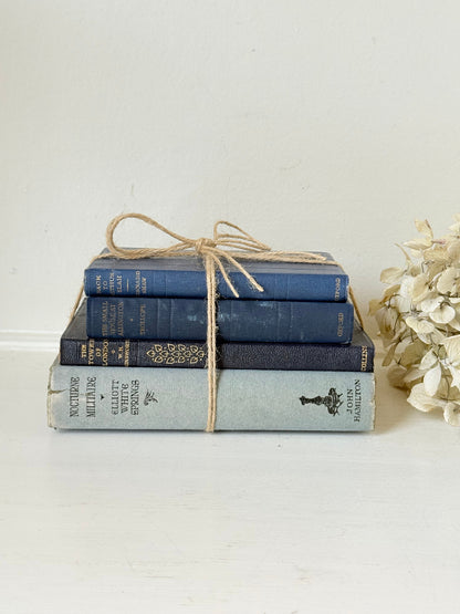 Vintage decorative book bundle in navy, grey, and cream tied with twine, photographed on a white surface