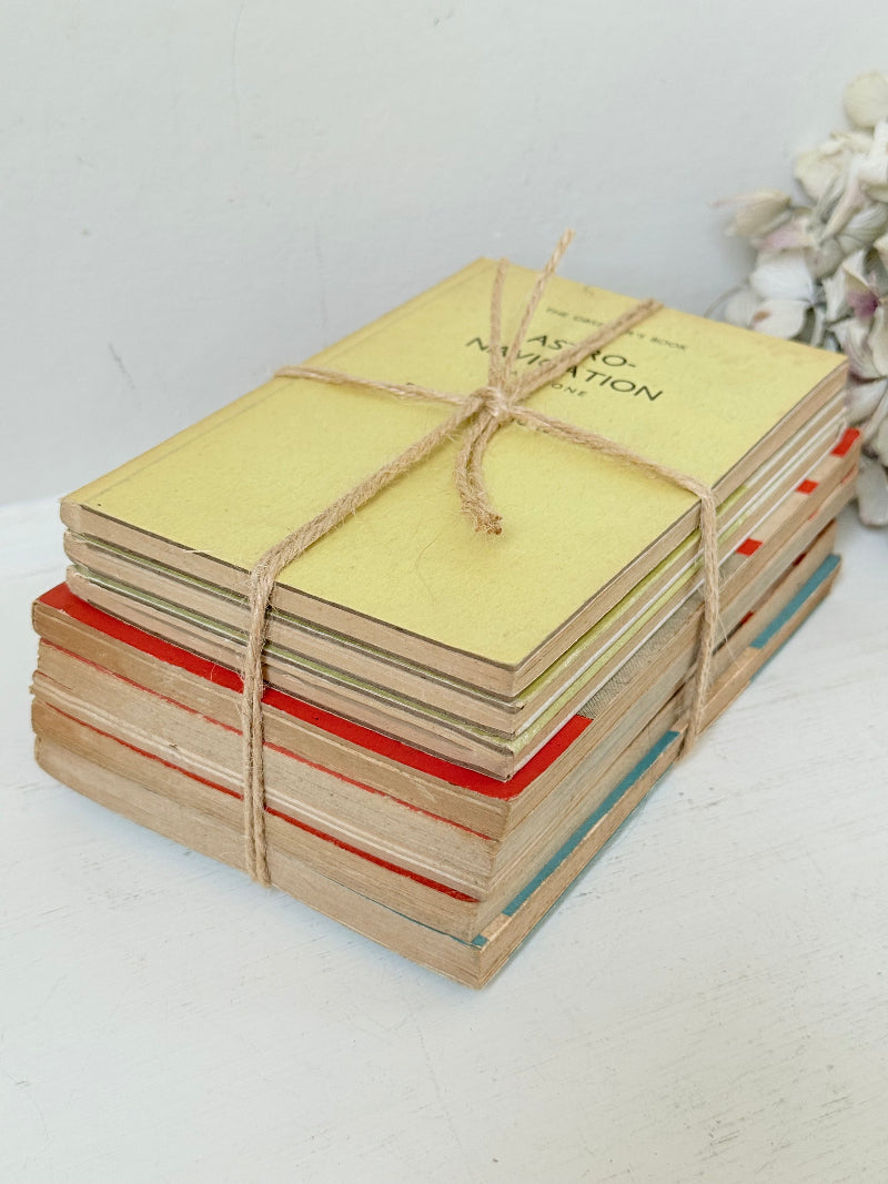 Bundle of vintage Penguin paperback books in orange and cream tones tied with twine, photographed on a white surface