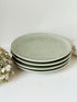 Set of four large Thai celadon stoneware plates in soft green glaze with raised pattern, photographed on a white surface