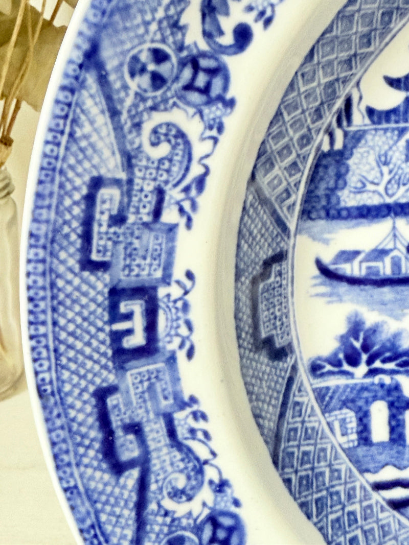 Antique Blue Willow serving bowl with cobalt transfer pattern shown on a white surface.