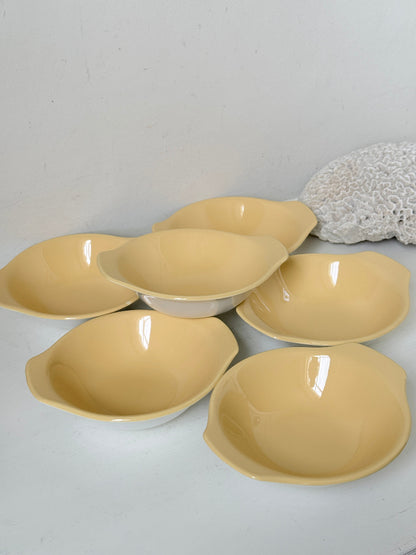 Set of six vintage Poole Pottery lemon bowls in butter yellow glaze photographed on a white surface