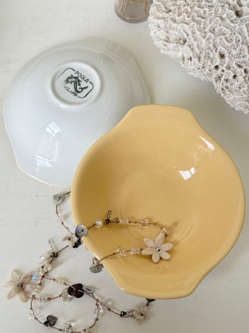 Set of six vintage Poole Pottery lemon bowls in butter yellow glaze photographed on a white surface
