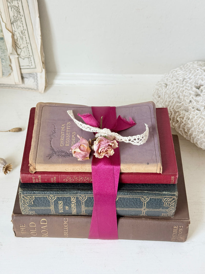 Vintage decorative book bundle with pink ribbon, dried flower detail and aged hardback covers for shelf and table styling