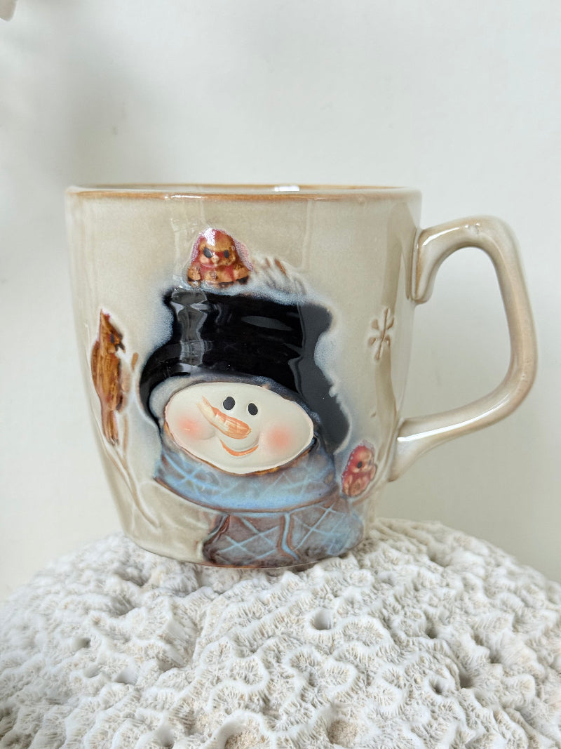 Pair of Christmas mugs with Santa and snowman designs photographed on a white surface.