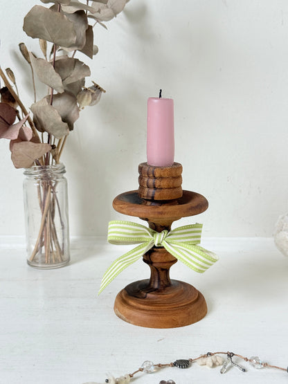 Vintage olivewood candlestick photographed on a white surface, turned wooden stem with warm grain and wide base holding a pink taper candle