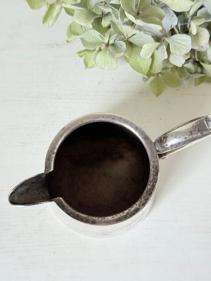 vintage silver plate jug with curved handle photographed on white surface with green hydrangeas