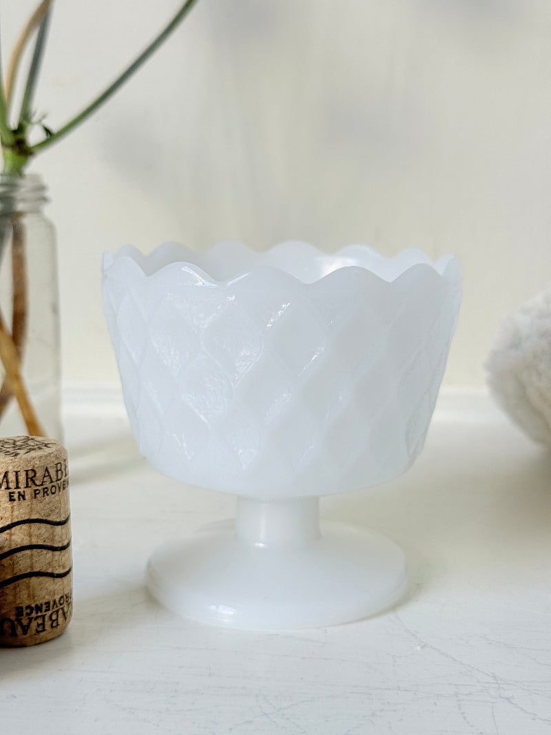 Vintage milk glass footed bowl with scalloped rim and pressed pattern, photographed on a white surface
