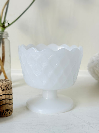 Vintage milk glass footed bowl with scalloped rim and pressed pattern, photographed on a white surface