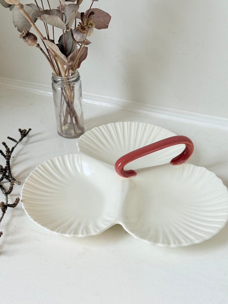 Poole Pottery double scallop hors d’oeuvre dish in white glaze with red handle photographed on a white surface