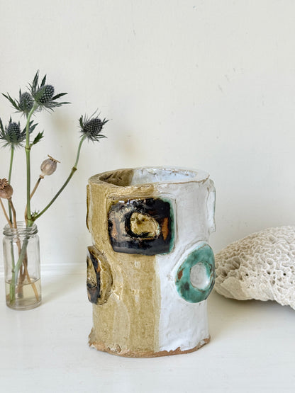 Vintage studio pottery vase in white, ochre and turquoise with abstract applied decoration, photographed on a white surface
