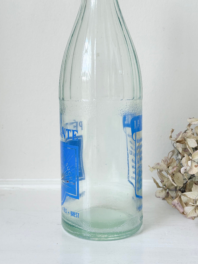 vintage french lemonade bottle la pétillante blue label on white surface with hydrangea flowers
